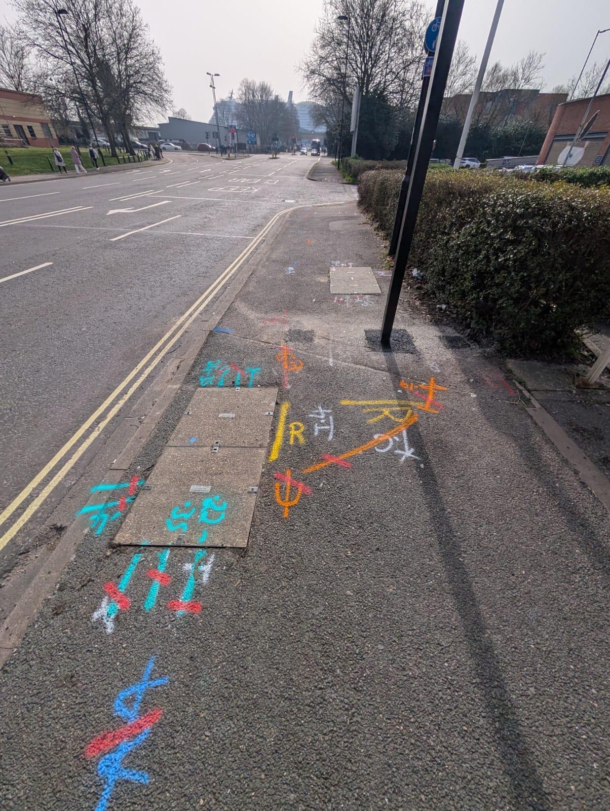 Street pavement with multicoloured utility markings and service covers